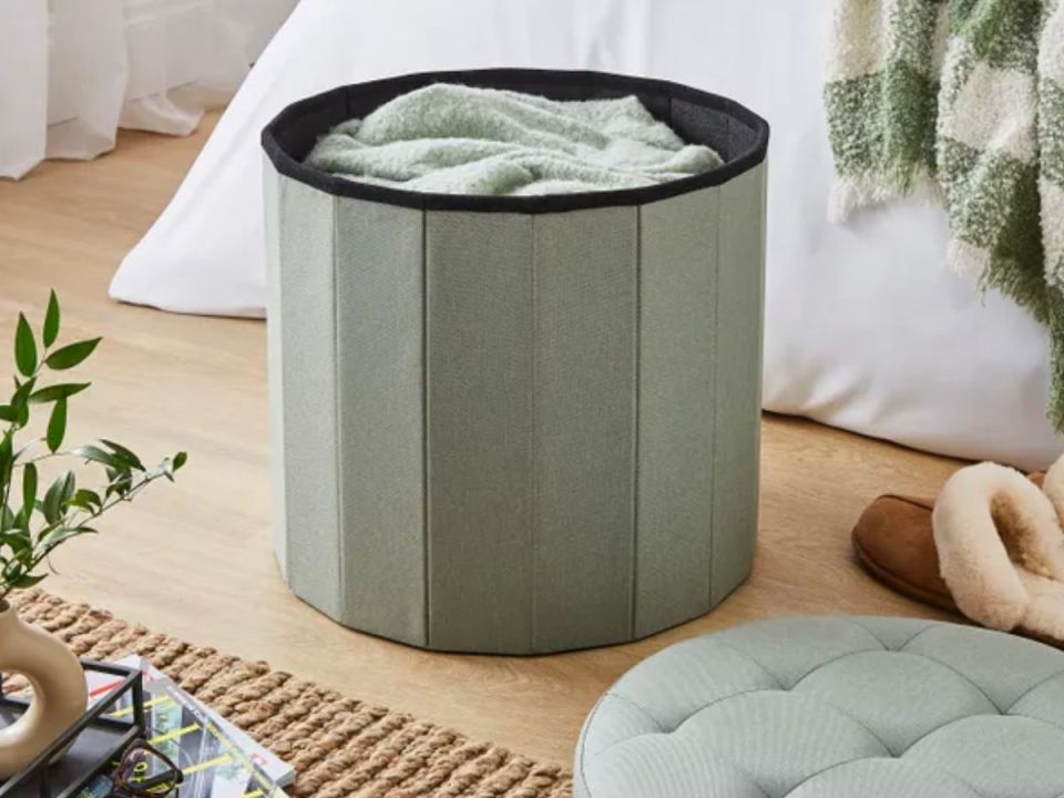 Light green laundry hamper with a cozy blanket inside.