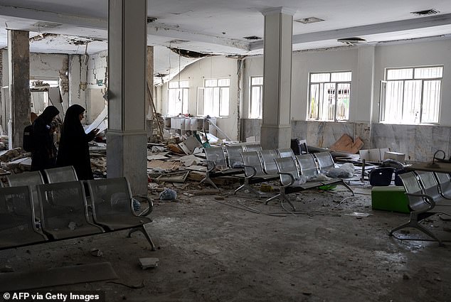 Two women are pictured walking amidst the debris at the Evin Prison's - where the Foreman's are being detained - visitor room after Israeli air strikes in 2025