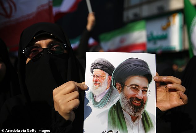 During celebrations in Tehran, a woman holds up a poster of Ayatollah Ali Khamenei and his son Mojtaba