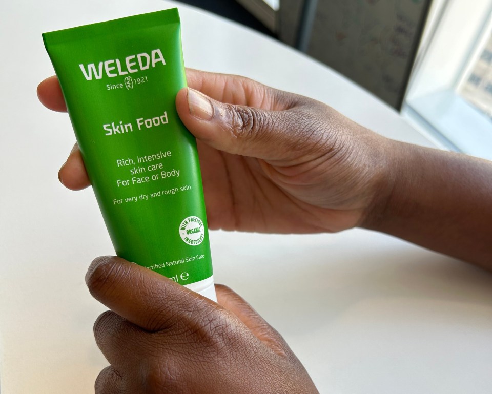 a person is holding a tube of weleda skin food