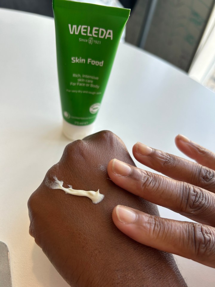 a tube of weleda skin food is being applied to a person 's hand