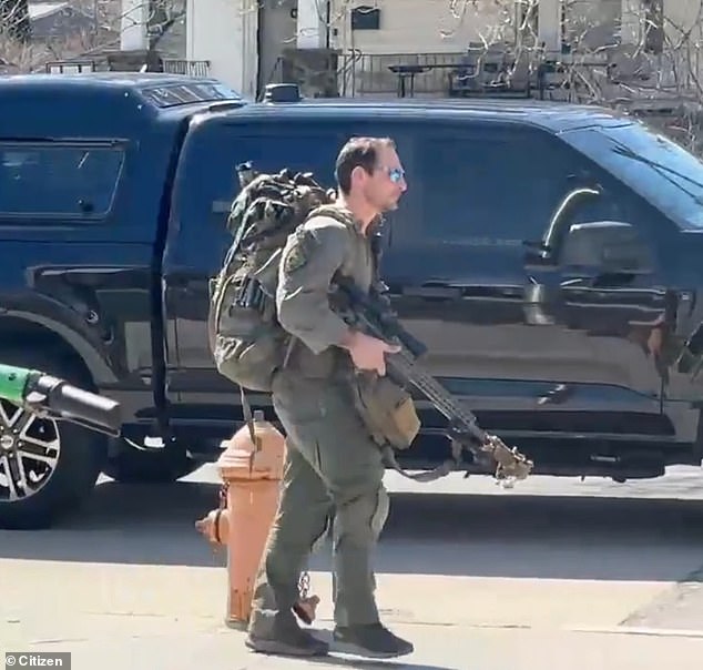 A law enforcement officer carrying what appears to be an assault-style weapon responds to the active shooter situation in Baltimore