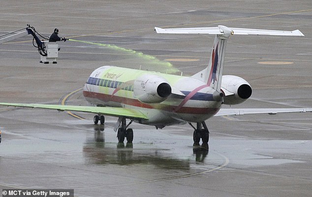 To remove ice, aircraft are sprayed with a de-icing solution and then treated with an anti-ice spray to prevent it from forming before they take off (stock image)