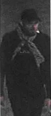 CCTV image of a man wearing a dark coat, hat, and scarf, with a cigarette in his mouth.