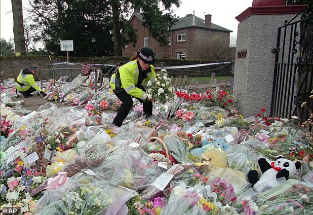 A police officer arranges flowers in rows at a side entrance to Dunblane Primary School in 1996