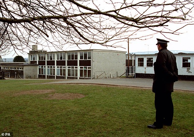 A policeman stands watch over the school where 16 children and their teacher were shot dead