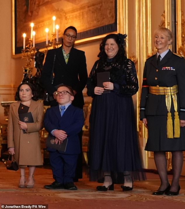 Along with his children Annabelle, 28, and son Harrison, 23, Warwick was also supported by a mystery woman (centre right) as he accepted his OBE