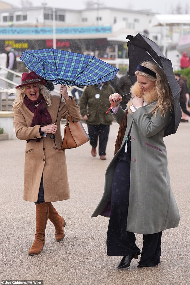 At least they're laughing about it! A duo share a laugh as they struggle to keep their umbrellas under control