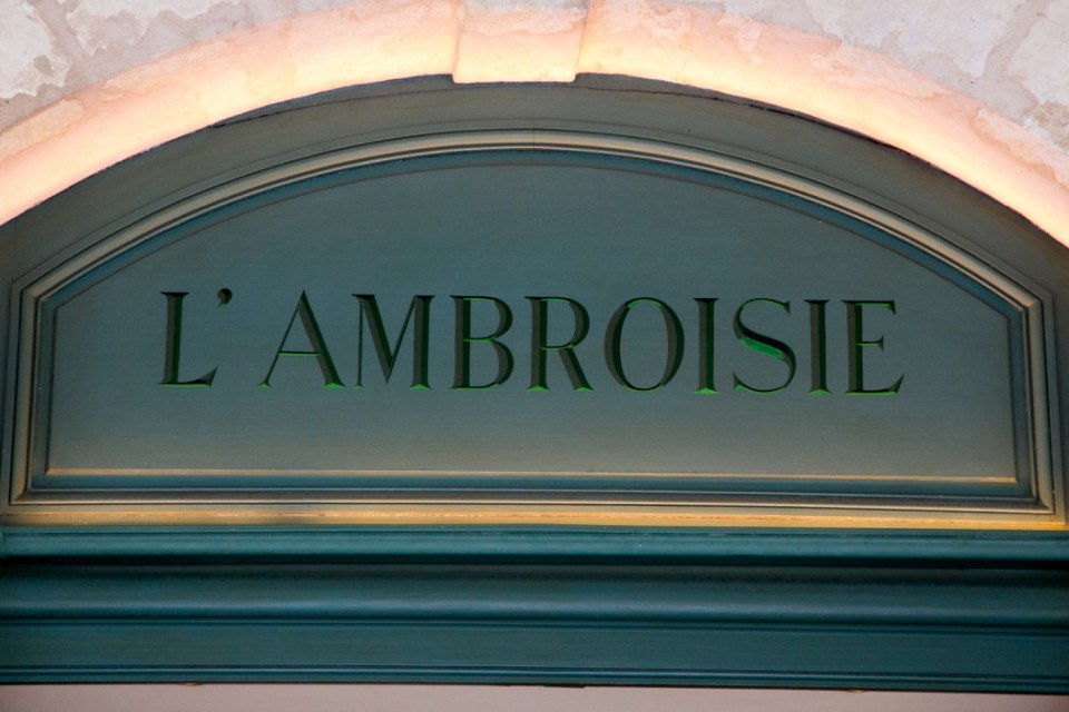 The name "L'Ambroisie" carved into the dark green facade of the Michelin 3-star restaurant.