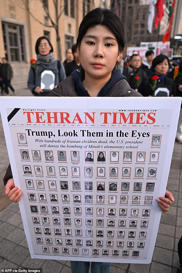 A protester in Seoul carries an anti-war placard featuring the faces of children killed in the February 28 strike