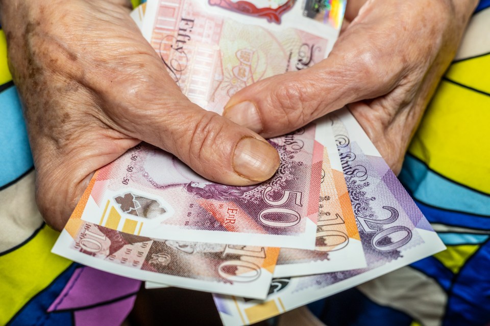 Elderly hands holding British pound notes.
