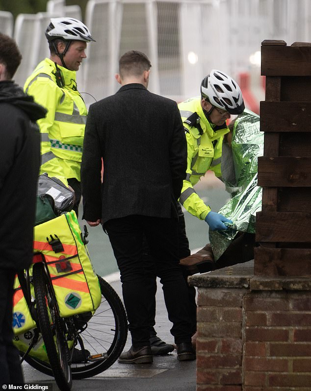 A man being wrapped in foil by paramedics near a wall at Cheltenham Festival yesterday