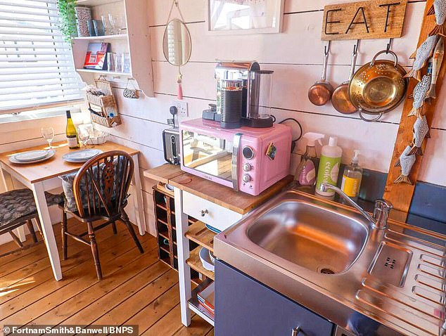 It has a kitchen area with electric hob, oven, microwave and fridge with ice box, a dining space with a table and chairs,