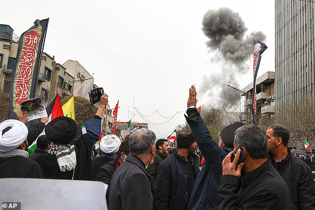 Smoke from an explosion rises behind demonstrators attending the annual anti-Israeli Quds Day, or Jerusalem Day, rally in support of Palestinians in Tehran, Iran, Friday, March 13