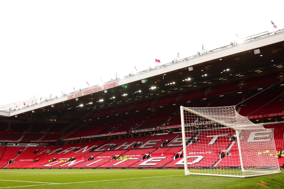 A football goal and the red stadium stands of Manchester United.