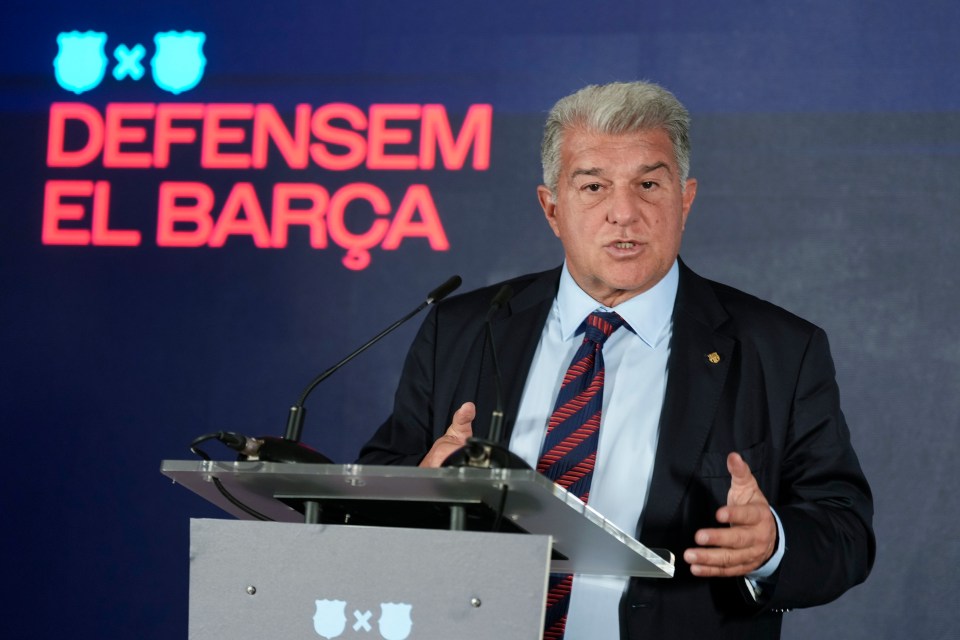 FC Barcelona President Joan Laporta speaking at a podium with the text "Defensem El Barça" (We Defend Barça) behind him.