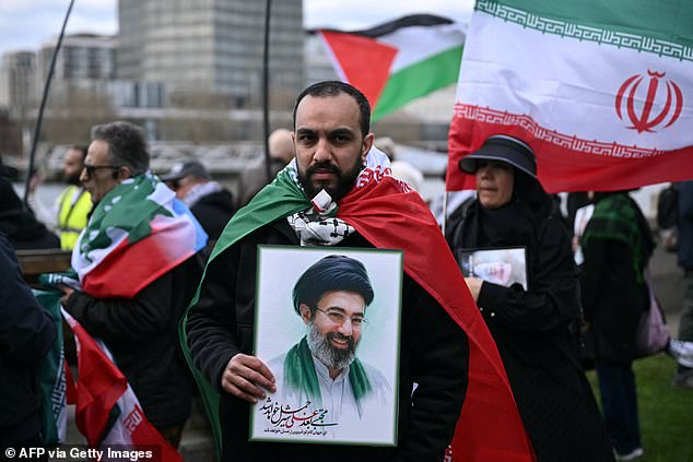An Iranian regime supporter holds an image of Iran's new Supreme Leader Mojtada Khamenei