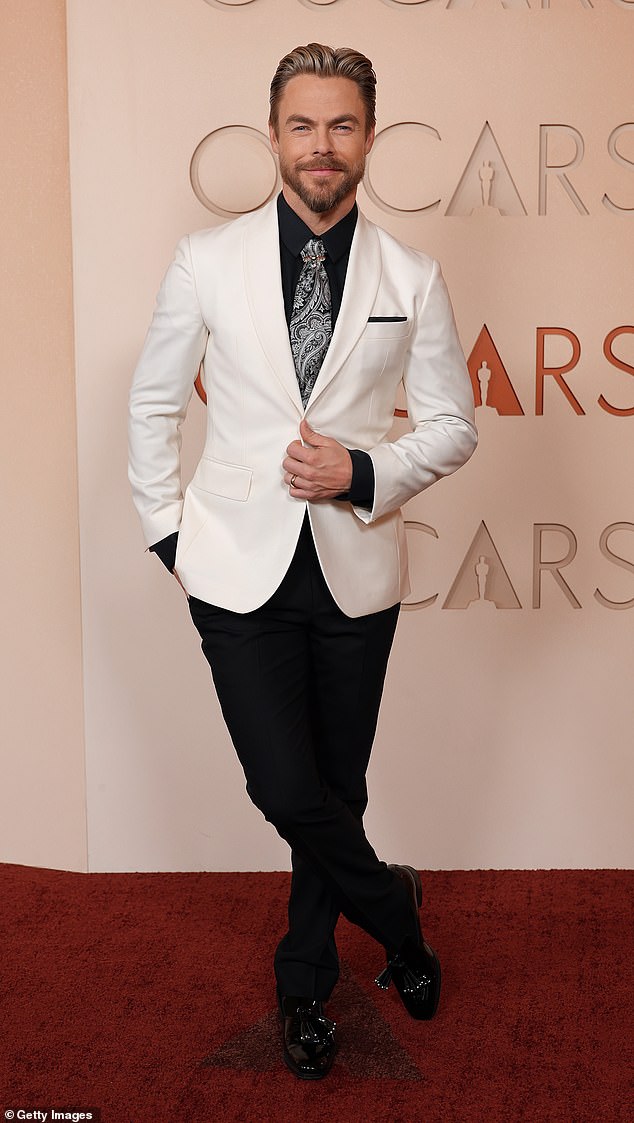 Derek Hough, 40, showcased his dapper sense of style in a crisp, white blazer in contrast with his black button-down and dress pants