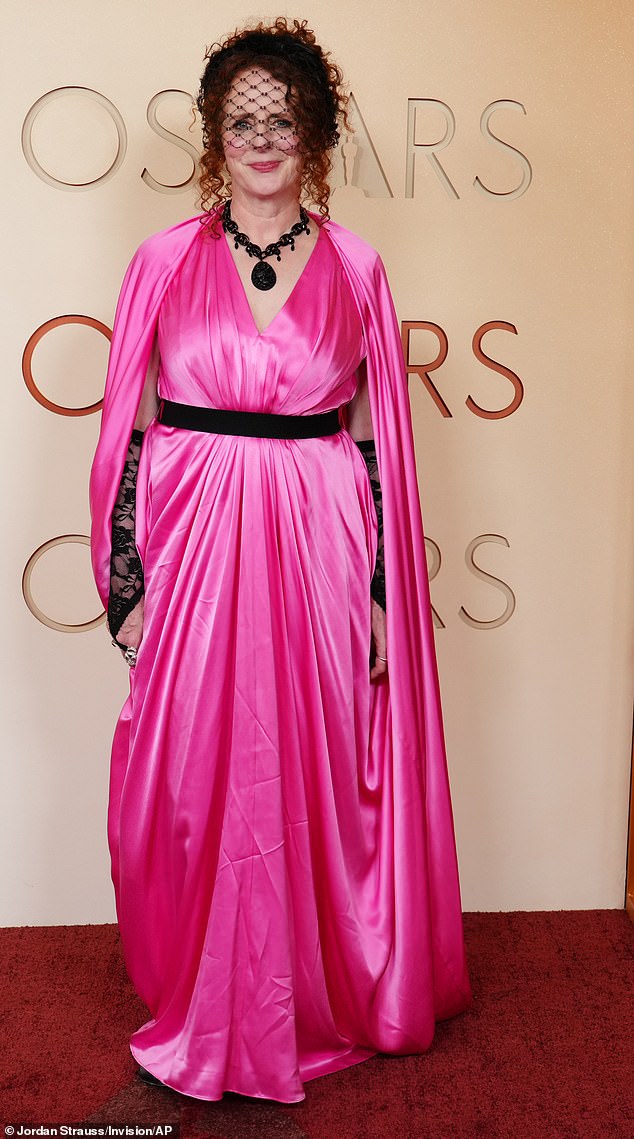 Costume party or Oscars? Novelist Maggie O'Farrell wore a bright pink, silky cape-dress on the red carpet, which was cinched at the waist with a black belt. She tied it together with a pair of black lace gloves and a black mask, along with a large black pendant necklace
