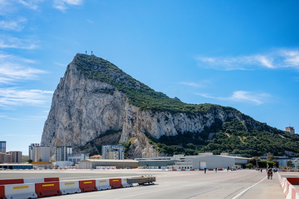 The Rock of Gibraltar with a marina on the left and a town in the background, viewed from La Linea, Spain.