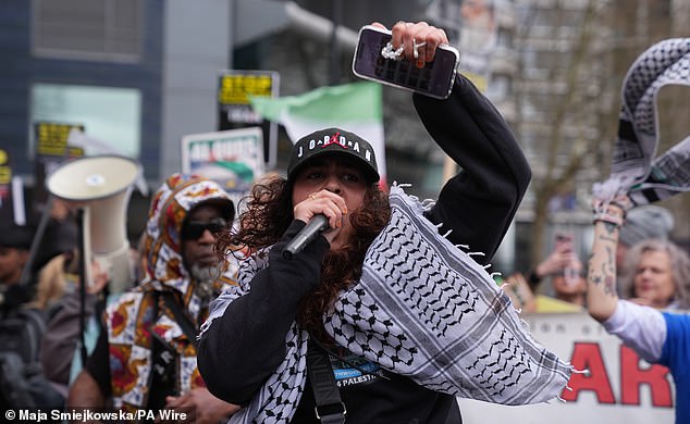 A pro-Iran demonstrator wearing a keffiyeh leads chants through a microphone