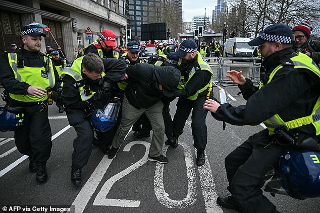 Police pictured arresting a protester at the static protest in central London today