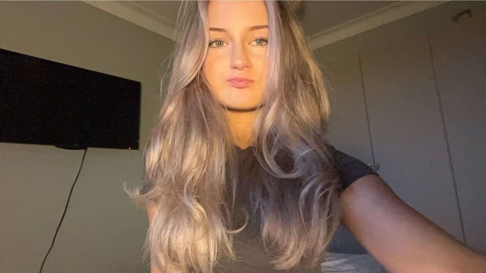 Olivia Wojciechowska, a 19-year-old university student, with long blonde hair, dark shirt, and a neutral expression.