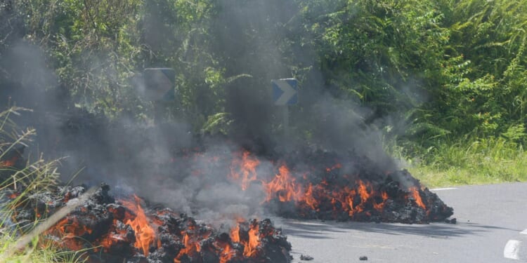 Stunning footage shows flaming lava slowly creep across road and meet the ocean after tropical island volcano eruption