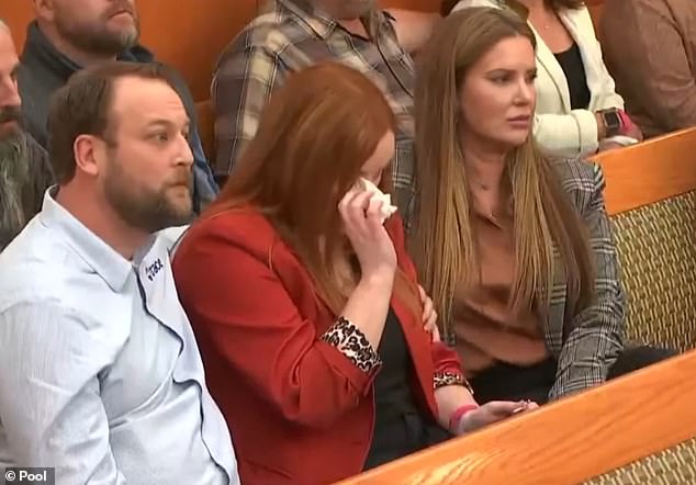 Eric's family and friends clutched one another for comfort with his sister Amy silently dabbing tears from her eyes