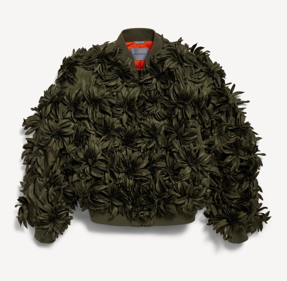 A Balenciaga Women's Flowers Cocoon Bomber in khaki, made from embroidered technical fabric, with a bright orange lining, and covered in leafy flower-like ruffles.