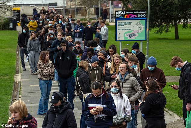 Staff and students, some wearing face masks, queue to receive antibiotics at the University of Kent in Canterbury