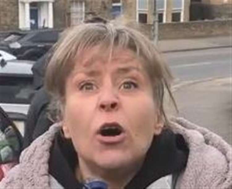 A woman with wide eyes and an open mouth, wearing a hooded jacket, reacting to an incident in Fort Pill Hill.