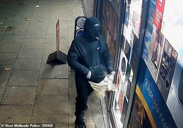 He is seen wearing a hood and balaclava and all dressed in black as he enters the shop (pictured) under the cover of darkness