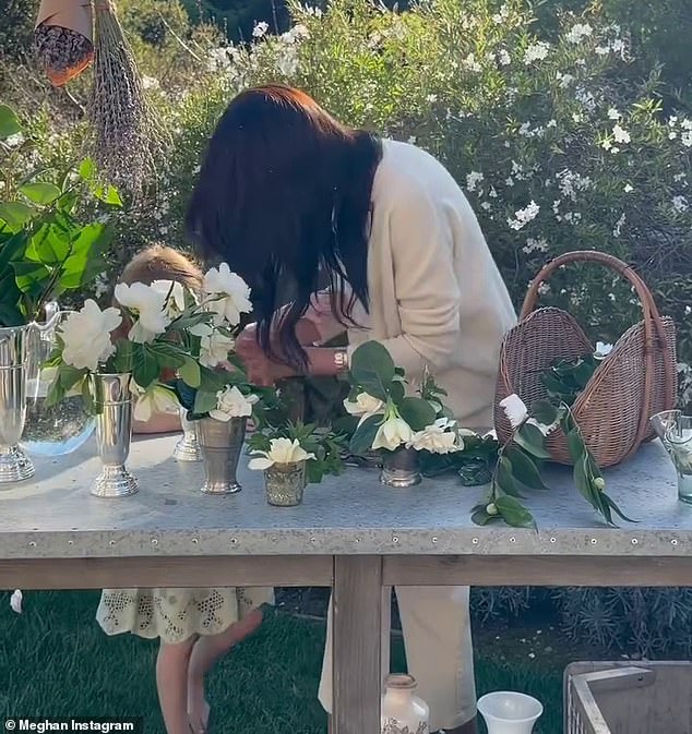 In the footage you can see Lilibet, with her long red hair in a beautiful sundress run up to the Duchess of Sussex as she is making flower arrangements and whisper something in her ear