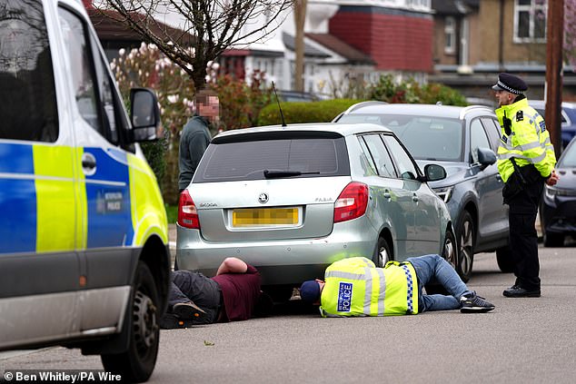At a property in Finchley, police were seen examining the undercarriage of a vehicle (pictured)