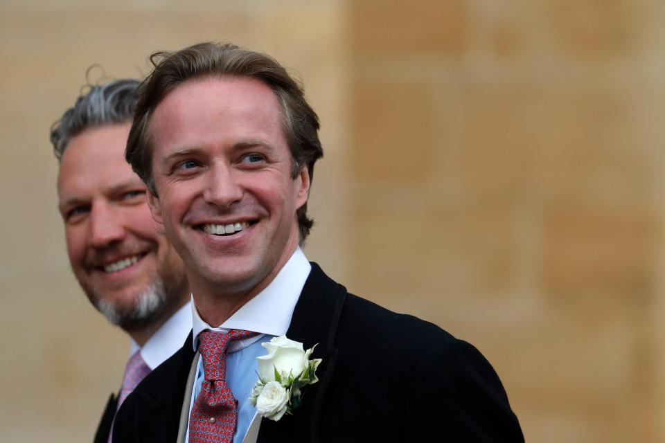 Thomas Kingston, wearing a boutonnière and black coat, smiles at his wedding.