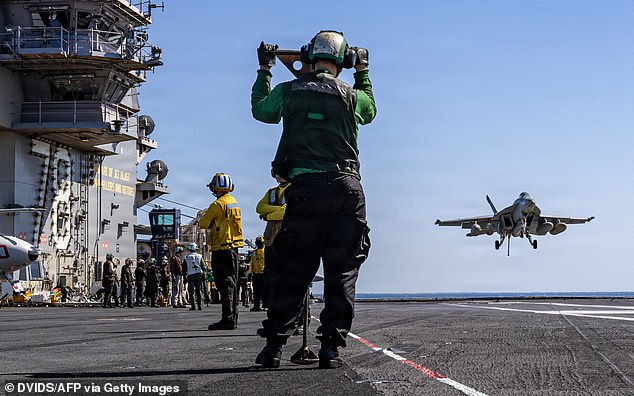 American sailors observing as an F/A-18E Super Hornet aircraft, assigned to Strike Fighter Squadron 31, approaches the flight deck of the world's largest aircraft carrier, USS Gerald R Ford (CVN 78), during Operation Epic Fury