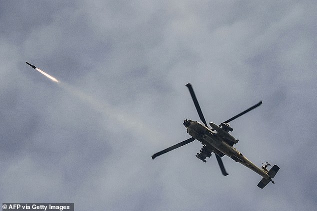 An Israeli Air Force AH-64 Apache attack helicopter fires rockets while flying along the border between northern Israel and southern Lebanon on Wednesday