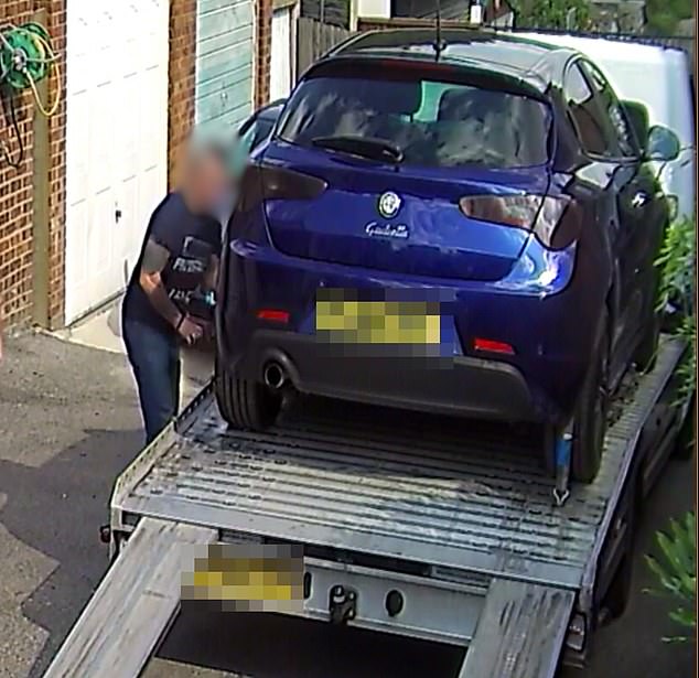 A car being delivered on the back of a flatbed lorry into the lane