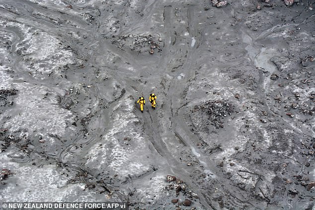 An aerial photograph shows two members of the New Zealand Defence Force taking part in a mission to recover bodies from White Island