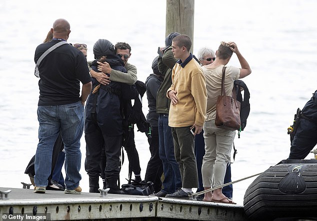 Families of victims killed in the White Island eruption are pictured upon their return from observing a minute's silence near the site, a week after the disaster