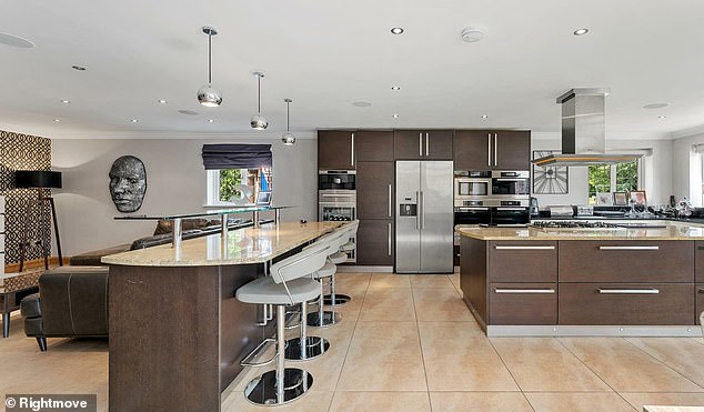 The property has multiple reception rooms and open-plan living spaces with a high-specification dark-panelled kitchen