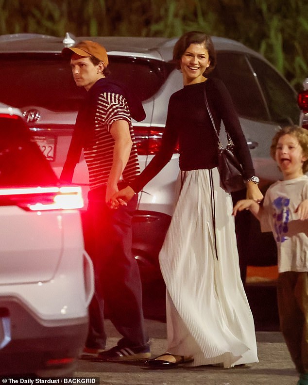 Holland kept it casual in loose trousers and striped shirt along with a baseball cap and a sweater flung over one shoulder