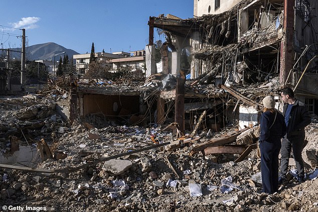Civilians look upon the remains of a residential and commercial building on Saturday in the Shahrak-e Gharb neighborhood of Tehran, Iran. The building was hit on March 16 amid US and Israeli attacks and resulted in several civilian deaths and missing persons