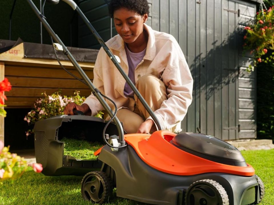 A person emptying the grass catcher of a lawnmower.