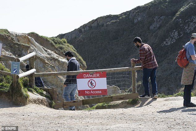 Tourists at Durdle Door recklessly ignore warning signs that were put up earlier this year a storm battered the coastline