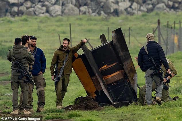 Israeli security personnel secure an area around a rocket partly buried in a field in the Israeli-annexed Golan Heights bordering Lebanon on Thursday