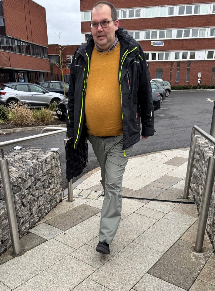 Ron Kleihues walks outdoors with a black jacket and yellow sweater.