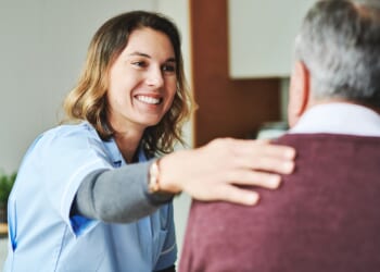 Woman in scrubs smiling with elderly man