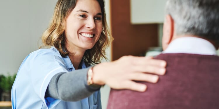 Woman in scrubs smiling with elderly man